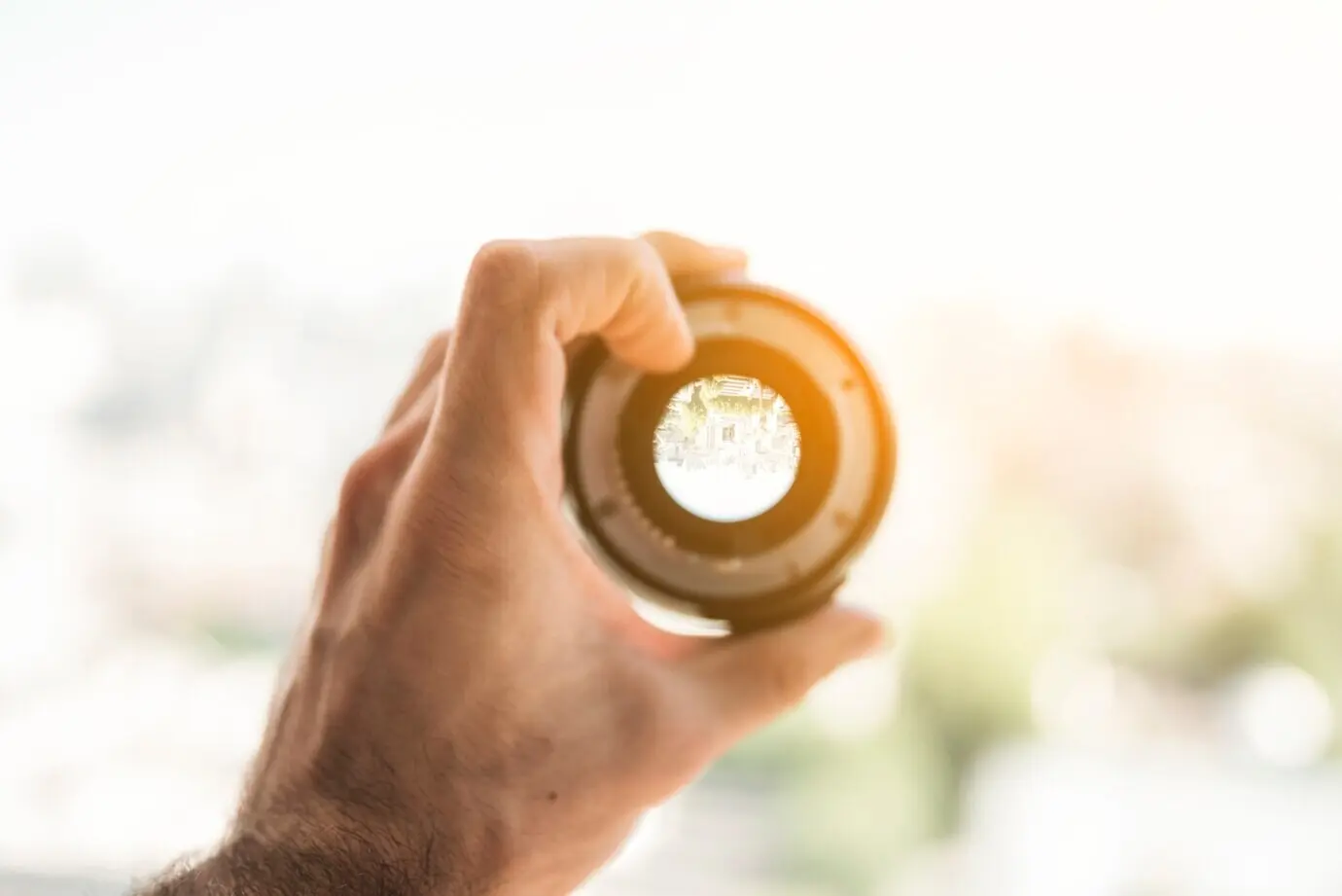 Die Hand eines Mannes hält ein professionelles digitales Kameraobjektiv.